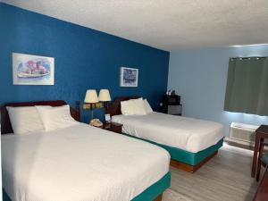 a hotel room with two beds and a blue wall at UP NORTH HOTEL formerly Voyager Inn in Saint Ignace +10 photos