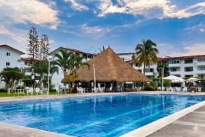 a resort swimming pool with a thatch roof at La Marina Condominiums by Monyxbnb in Puerto Vallarta