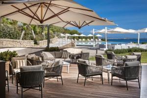 a patio with chairs and tables and an umbrella at L'Ea Bianca Luxury Resort in Baja Sardinia