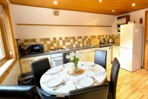 a kitchen with a table and chairs and a kitchen with a refrigerator at Primrose Lodge with Hot Tub near Waterpark and Trails in Chudleigh