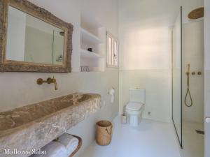 a bathroom with a tub and a toilet and a mirror at C'an Llum in Deia