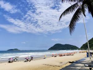 a beach with a bunch of people and umbrellas at 8 Apartamentos em Condomínio Fechado c/portaria presencial 24 hs à Beira mar na Praia do Tombo no Guarujá in Guarujá