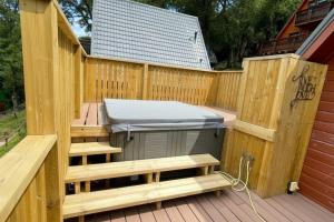 a barbecue on a deck with a wooden fence at Primrose Lodge with Hot Tub near Waterpark and Trails in Chudleigh