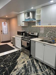 a kitchen with white cabinets and a stove and a sink at Stylish City Escape in Toronto