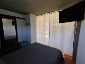 a bedroom with a bed and a window with curtains at Hospedaje El Rancho in Castillos +12 photos