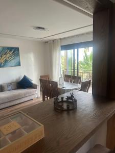 a living room with a table and chairs and a couch at Joli appartement à Tamaris in Dar Bouazza
