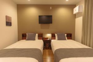 two beds in a room with a tv on the wall at Solis Studio Miyako SeaSide in Miyako-jima