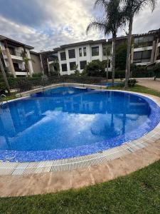a large blue swimming pool in front of a building at Joli appartement à Tamaris in Dar Bouazza