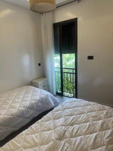 a bedroom with a bed and a window with a balcony at Joli appartement à Tamaris in Dar Bouazza +28 photos