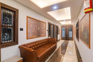 a brown leather couch in a hallway with paintings at HOTEL O PRAGATI in Gorakhpur