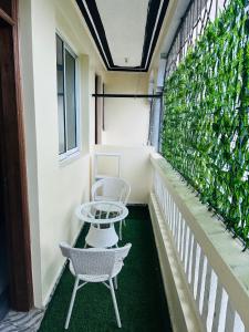a balcony with two chairs and a table and a green wall at Honed homes in Mombasa