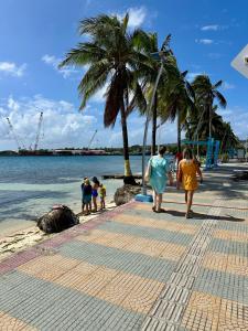 a group of people walking on a beach with palm trees at Los Almendros Beach in San Andrés
