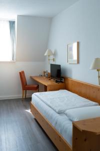 a bedroom with a bed and a desk with a computer at Hotel Grünshof in Walldorf