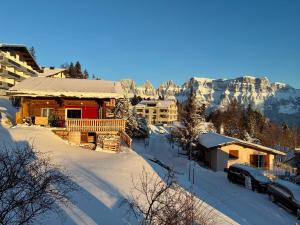 a log cabin in the snow with mountains in the background at Steinbock 2OG - CharmingStay in Flumserberg +16 photos