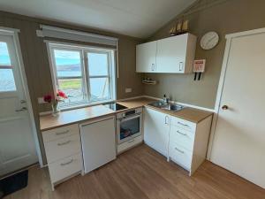 a small kitchen with white cabinets and a sink at Krókur Guesthouse in Patreksfjörður