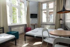 a room with two beds and a table and chairs at Sleep in Hostel & Apartments Stary Rynek in Poznań