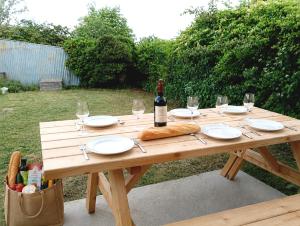a wooden picnic table with a bottle of wine and glasses at Gîte ô scope-2km du futuroscope- linges et ménage inclus in Jaunay-Clan