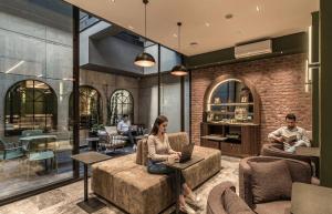 a woman sitting in a chair in a lobby with a laptop at Kukun Edition El Angel in Mexico City