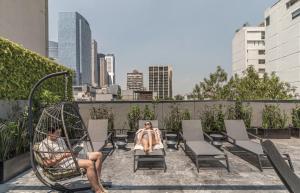 two people sitting in chairs on a rooftop at Kukun Edition El Angel in Mexico City