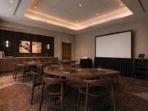 a conference room with tables and chairs and a screen at Hotel Trinity, Autograph Collection in Austin