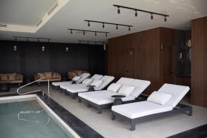 a waiting room with white chairs and a swimming pool at Domun Hotel in Querétaro