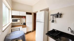 a small kitchen with a refrigerator and a sink at Casa de Hóspedes Jaú in Jaú
