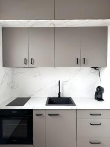 a white kitchen with a sink and white cabinets at Zafiro Apartment, City Center in Kavadarci