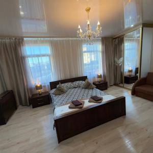 a bedroom with a large bed and a chandelier at Vadim Home in Ventspils