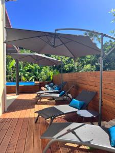 a row of tables and umbrellas on a deck at Voilier Bermuda By Villa AGADA in Gourbeyre