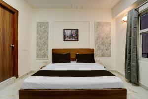 a bedroom with a large bed with black and white sheets at Super Townhouse Rosens hotel in Noida +22 photos