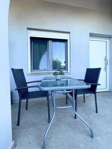 a glass table with two chairs and a window at Elia Room & Garden in Kontokali
