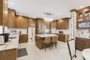 a kitchen with wooden cabinets and a island with bar stools at Cozy Queen Room in Quiet Richmond Seafair Area in Richmond