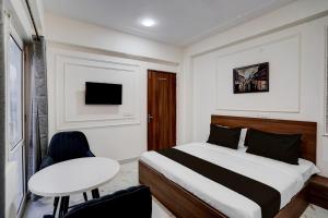 a bedroom with a bed and a table and a tv at Super Townhouse Rosens hotel in Noida