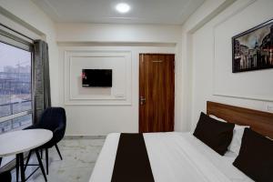 a bedroom with a bed and a table and a window at Super Townhouse Rosens hotel in Noida