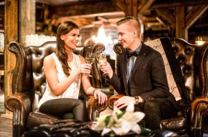 mężczyzna i kobieta siedzący w skórzanych fotelach pijący szampana w obiekcie Boutique Hotel Mustaparta w mieście Tornio