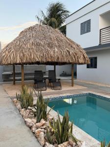 a straw umbrella and chairs next to a swimming pool at Blanquila Resort in Willemstad