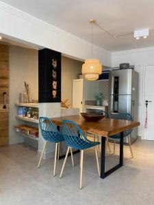 a kitchen with a wooden table and blue chairs at 8 Apartamentos em Condomínio Fechado c/portaria presencial 24 hs à Beira mar na Praia do Tombo no Guarujá in Guarujá