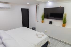 a white bedroom with a bed and a flat screen tv at 33 HOTEL BOUTIQUE in Medellín