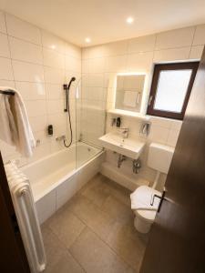 a bathroom with a tub and a toilet and a sink at Parkhotel Lindenhof - KOSTENLOSE PARKPLÄTZE in Offenbach