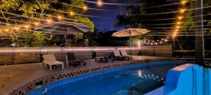 a swimming pool with two chairs and umbrellas next to at Rainforest Lodge del Rio in Portobelo