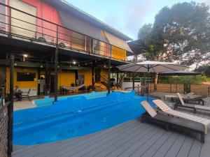 a swimming pool with chairs and an umbrella next to a building at Rainforest Lodge del Rio in Portobelo +24 photos