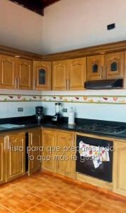 a kitchen with wooden cabinets and a stove top oven at Hospedaje Helena in Circasia