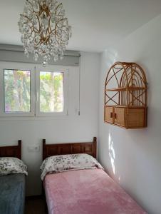 a bedroom with two beds and a chandelier and two windows at Apartamentos Escorpion Tossa de Mar in Tossa de Mar