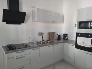 a white kitchen with a sink and a microwave at La Casamarie in Saint-Louis