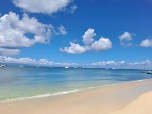 a beach with boats in the water and clouds in the sky at La Casamarie in Saint-Louis