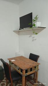a wooden table with chairs and a tv on a wall at Hospedaje "Doña Tomasa" -A 15 minutos del aeropuerto -Parking in Ezeiza +3 photos