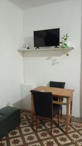 a dining room table with two chairs and a television on a wall at Hospedaje "Doña Tomasa" -A 15 minutos del aeropuerto -Parking in Ezeiza