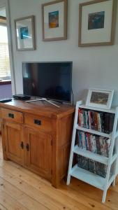 a wooden entertainment center with a flat screen tv and a book shelf at Jack's place in Balnakeil