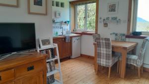 a kitchen with a wooden table and a television at Jack's place in Balnakeil