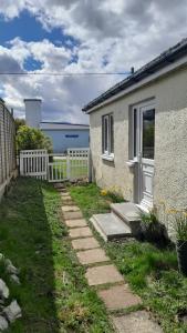 a house with a white door and a fence at Jack's place in Balnakeil